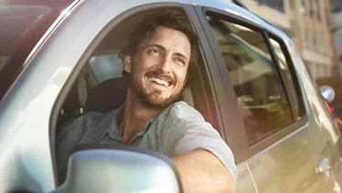 Mann lächelt aus Fahrzeugfenster