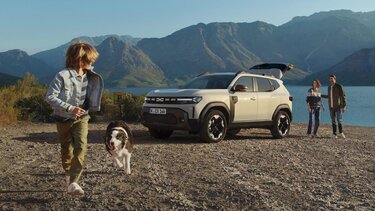 Pärchen mit Hund läuft an an einem Dacia Duster vorbei