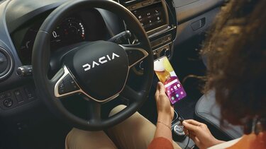 visuel intérieur femme avec portable devant volant Dacia