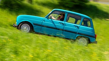 alter Renault 4 fährt Straße hinauf, vorne Wiese