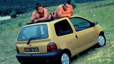 Zwei Sumoringer auf der Dachhaube eines alten Renault Twingo