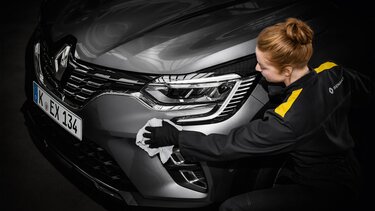 Frau poliert Karosserie eines Renault Fahrzeugs
