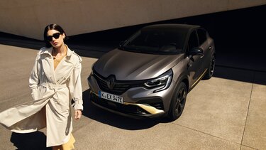 Dunkelhaarige Frau vor einem Renault Captur E-Tech