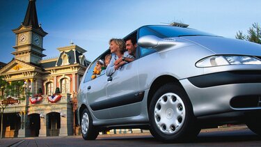 Familie mit zwei Kindern schaut aus den Fenstern eines grauen Renault Espace