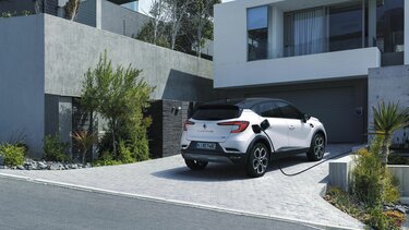 Neuer Renault Captur Plug-In Hybrid wird vor einem Haus aufgeladen