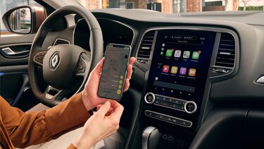 Frau lädt iPhone im Renault Megane Grandtour
