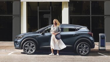 Frau steht vor ihrem Renault und möchte Straße überqueren