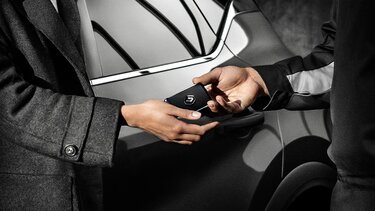Mitarbeiter mit Handschuh händigt Kunden Renault Schlüsselkarte aus