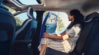 Dunkelhaarige Frau auf der Rückbank eines Renault Captur mit geöffneter Tür